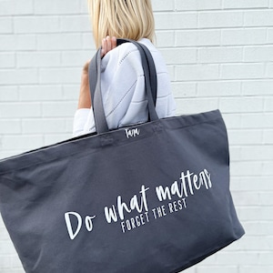 Oversized tote in a thick durable grey canvas which says “Do what matters, forget the rest”. These totes come in 4 different text options, two text colors and 4 tote color options.