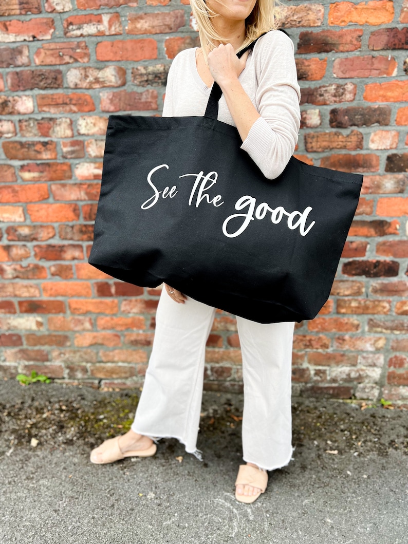 Oversized tote in a thick durable black canvas which says “See the good”. These totes come in 4 different text options, two text colors and 4 tote color options.