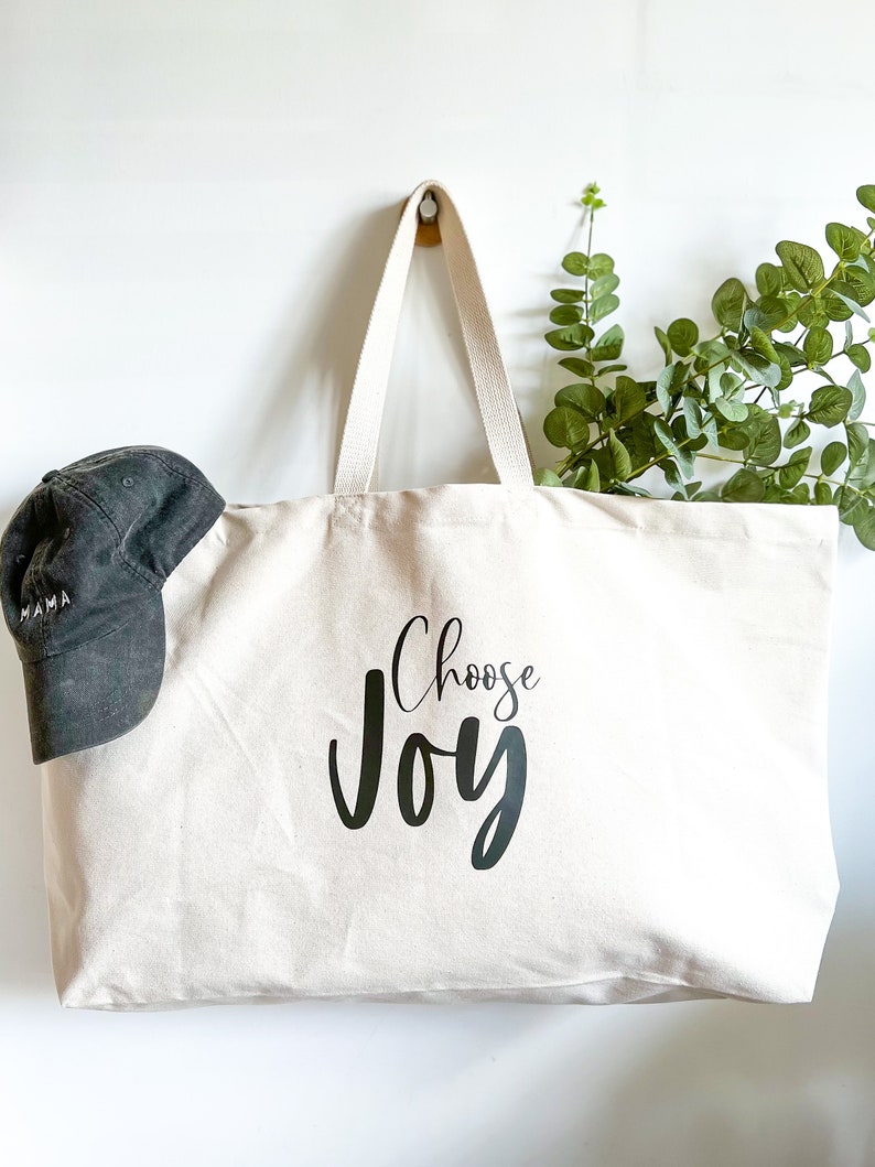 Oversized tote in a thick durable natural canvas which says “Choose Joy”. These totes come in 4 different text options, two text colors and 4 tote color options.