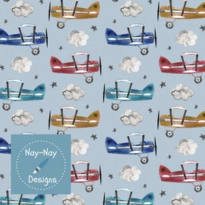 May include: A seamless pattern featuring watercolor illustrations of airplanes in various colors, including blue, red, and brown, flying against a light blue background with white clouds and black stars. The pattern includes the text "Nay-Nay Designs".