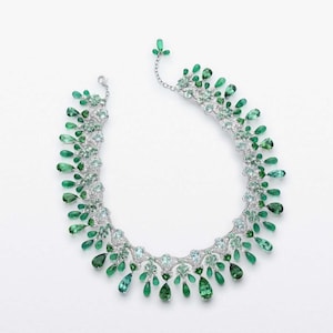 May include: A delicate necklace with a gradient of green gemstones, including emeralds and aquamarines, set in silver.