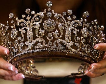 May include: A sparkling diamond tiara with a delicate floral design. The tiara is made of gold and features a row of diamonds around the edge.