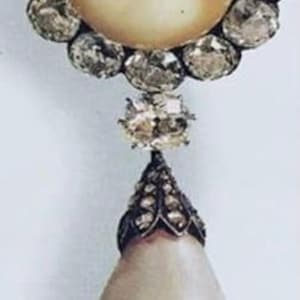 May include: A pearl pendant necklace with a large, teardrop-shaped pearl and a silver setting. The pearl is surrounded by a cluster of smaller diamonds.