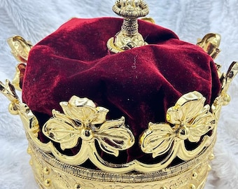 Może przedstawiać: Złota korona z czerwoną aksamitną podszewką. Korona ma ozdobny wierzchołek i skomplikowane detale. "Haren's Victorian Handmade Jewellery" jest napisane na spodzie korony.