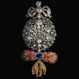 May include: A gold and silver jeweled pendant with a large blue sapphire, red and gold accents, and a design of a crown, a fan, and two lions.