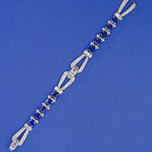 Könnte beinhalten: Ein silbernes Armband mit einem Gliederdesign, das abwechselnd blaue Saphire und Diamanten zeigt.