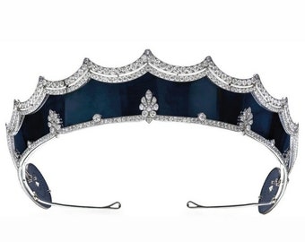 May include: A silver tiara with a black enamel band and diamond accents. The tiara has a scalloped edge and a pointed crown.