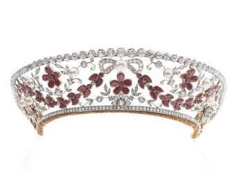 Puede incluir: Una diadema delicada con un diseño floral con piedras de color rojo rubí y perlas engastadas en plata.