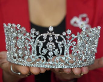 May include: A silver crown with a floral design and many sparkling diamonds.