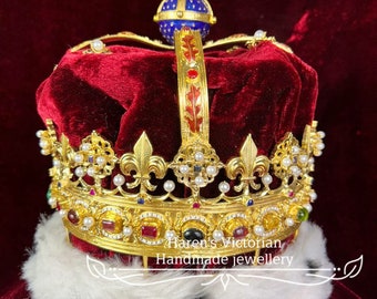 May include: A gold crown with red velvet lining, adorned with pearls, gemstones, and a cross on top. The crown is on a white fur trim and a red velvet background. "Karen's Victorian Handmade Jewellery" is written below the crown.