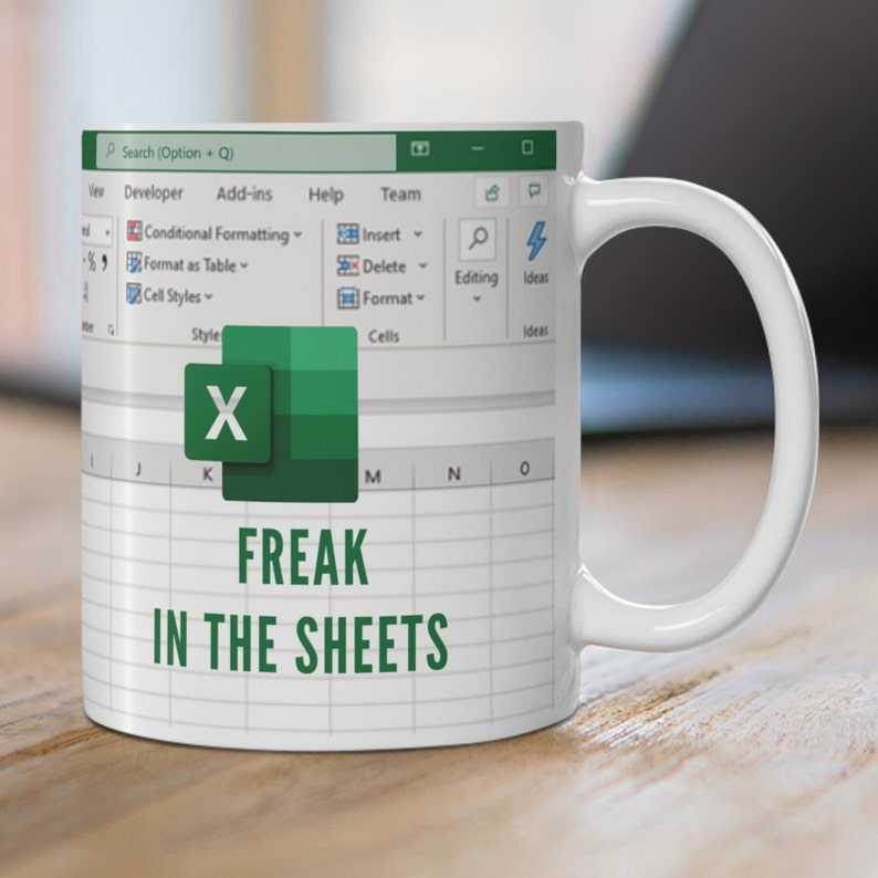 K&ouml;nnte beinhalten: Eine wei&szlig;e Kaffeetasse mit einem gr&uuml;nen Excel-Tabellenblatt-Design. Die Tasse tr&auml;gt den Text "FREAK IN THE SHEETS".