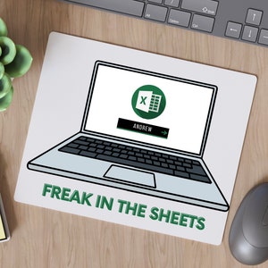 K&ouml;nnte beinhalten: Ein wei&szlig;es Mauspad mit einer Schwarzwei&szlig;illustration eines Laptops mit dem Microsoft Excel-Logo und dem Text "FREAK IN THE SHEETS".