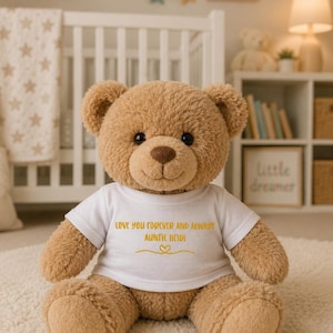Puede incluir: Un oso de peluche de color marr&oacute;n claro sentado, que lleva una camiseta blanca con el texto amarillo "LOVE YOU FOREVER AND ALWAYS AUNTIE HEIDI" impreso en la parte delantera, junto a un peque&ntilde;o coraz&oacute;n amarillo y una l&iacute;nea decorativa.