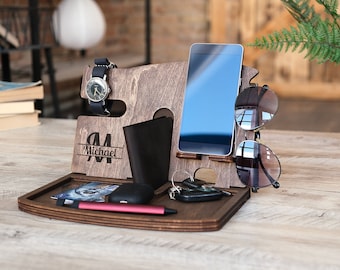 May include: Wooden desk organizer with compartments for a phone, watch, wallet, keys, and sunglasses. The organizer is engraved with the name "Michael". A watch with a black band and a pair of sunglasses are visible.