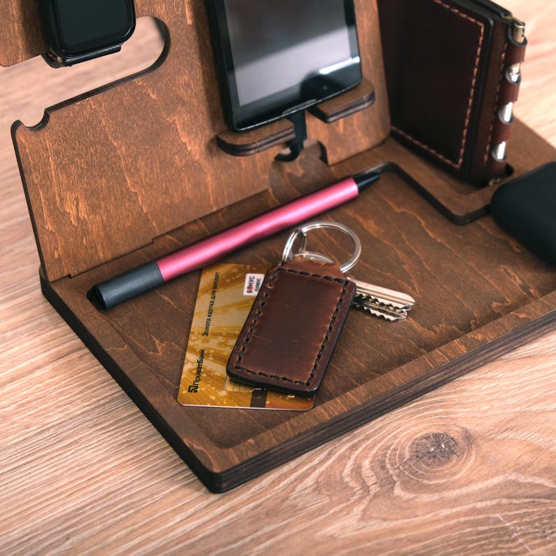 Pu&ograve; includere: Un organizzatore in legno con slot per telefono, orologio, chiavi e penna. C'&egrave; una carta di credito e un portachiavi in ​​pelle nell'organizzatore.
