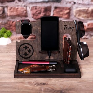 Pu&ograve; includere: Un supporto per telefono in legno con un logo Steelers, un porta orologio, uno slot per telefono, un porta occhiali da sole, uno slot per portafoglio, un portachiavi e un portapenne. Il supporto &egrave; personalizzato con il nome "Tony".