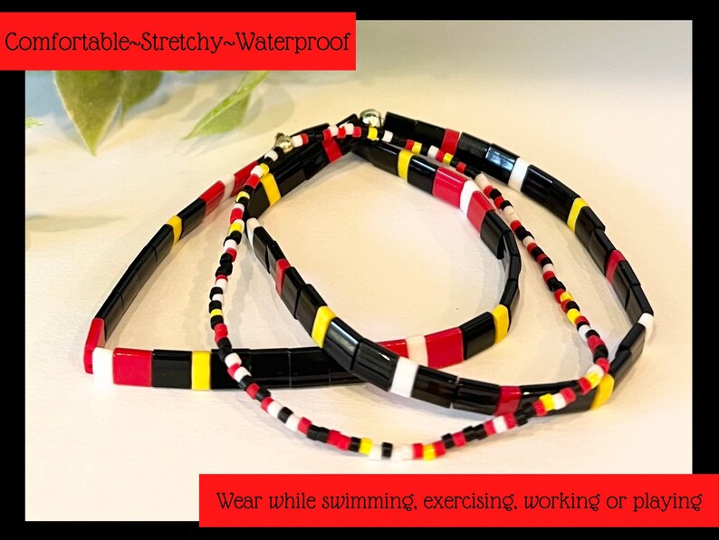 May include: Three colorful beaded bracelets in black, red, white, and yellow. The bracelets are made of square beads and are stacked on top of each other. The text "Comfortable-Stretchy-Waterproof" is at the top of the image. The text "Wear while swimming, exercising, working or playing" is at the bottom of the image.