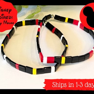 May include: Two black, red, yellow, and white beaded bracelets inspired by Mickey Mouse.