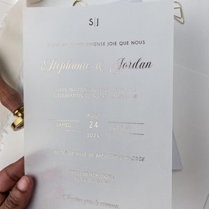 Könnte beinhalten: Eine weiße Hochzeitseinladung mit goldenen Lettern. Die Einladung lautet "C'est avec une immense joie que nous Stephanie & Jordan Vous invitons joyeusement à la célébration de notre mariage le Samedi 24 Aout 2024 15h30 à l'hôtel de ville de Bretigny-sur-Orge Merci de répondre au 06 00 00 00 Reception après la cérémonie."