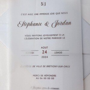 May include: A wedding invitation with a white background and silver text. The invitation reads "C'est avec une immense joie que nous St&eacute;phanie & Jordan vous invitons joyeusement &agrave; la c&eacute;l&eacute;bration de notre mariage le Samedi 24 Aout 2024 15h30 &agrave; l'h&ocirc;tel de ville de Br&eacute;tigny-sur-Orge Merci de r&eacute;pondre au 06 00 00 00 R&eacute;ception apr&egrave;s la c&eacute;r&eacute;monie."