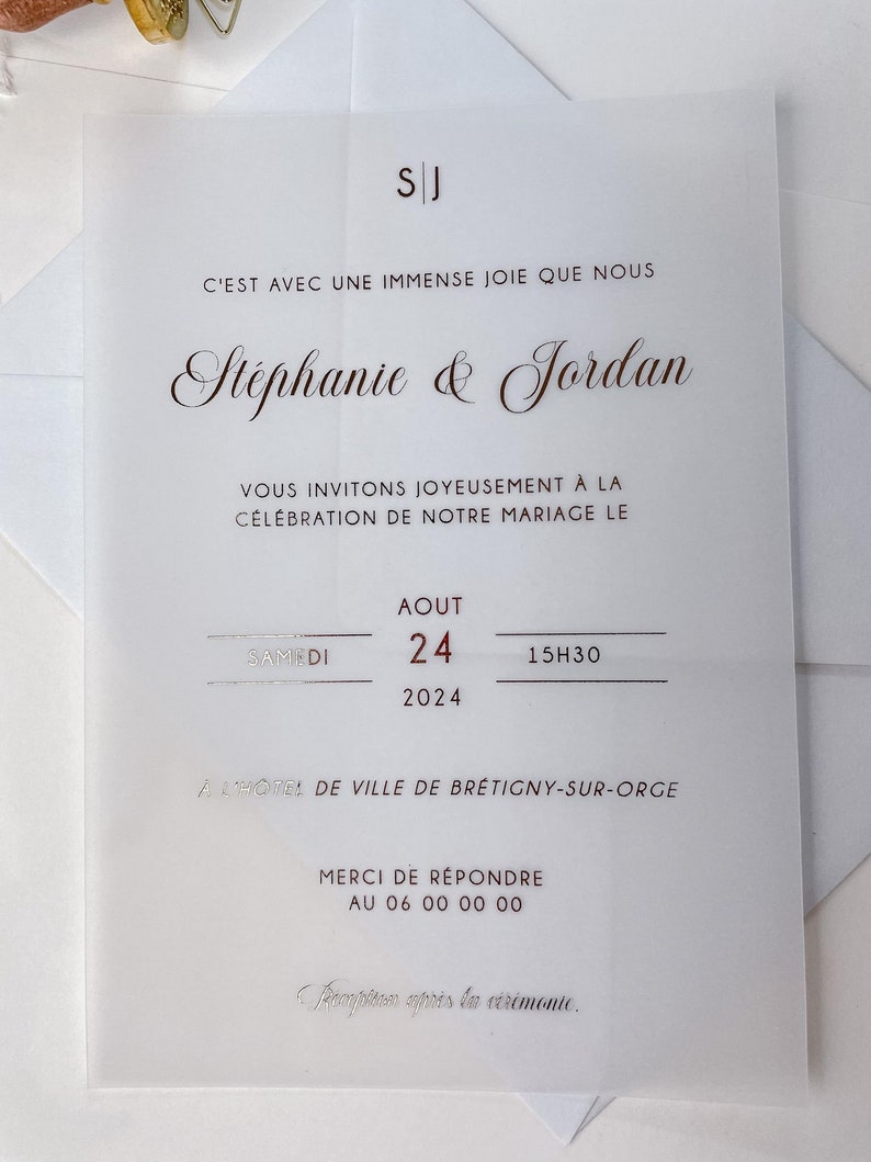 May include: A wedding invitation with a white background and silver text. The invitation reads "C'est avec une immense joie que nous St&eacute;phanie & Jordan vous invitons joyeusement &agrave; la c&eacute;l&eacute;bration de notre mariage le Samedi 24 Aout 2024 15h30 &agrave; l'h&ocirc;tel de ville de Br&eacute;tigny-sur-Orge Merci de r&eacute;pondre au 06 00 00 00 R&eacute;ception apr&egrave;s la c&eacute;r&eacute;monie."