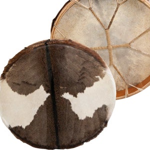 Puede incluir: Un tambor de piel de animal marrón y blanco con un marco de madera y un cordón de cuero. El tambor se muestra tanto desde la parte superior como desde la inferior.