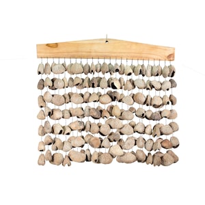 May include: A wall hanging composed of numerous beige, textured, organic-shaped pieces suspended from a wooden beam. The pieces are strung together with thin, dark cords, creating a natural, earthy aesthetic. The wooden beam has a light brown colour.