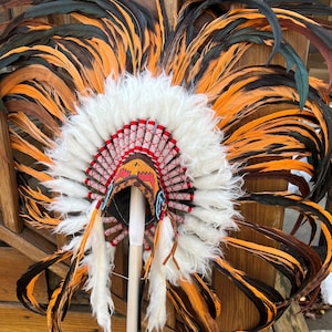 May include: A Native American headdress with orange and black feathers, white fur trim, and red and white beaded accents.