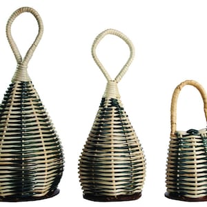 Könnte beinhalten: Drei geflochtene Rasseln, auch bekannt als Maracas, in verschiedenen Größen. Die Rasseln sind aus natürlichen Materialien gefertigt und haben ein schwarz-weiß gestreiftes Muster. Die Rasseln haben einen Schlaufe oben.