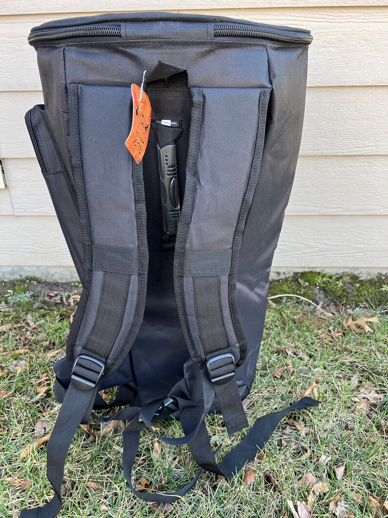 May include: Black backpack with adjustable shoulder straps and a handle. The backpack has a zippered top and a tag hanging from the handle. The backpack is made of a durable material and is designed for carrying items.