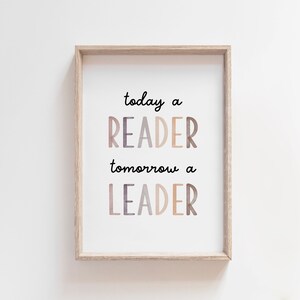 Könnte beinhalten: Ein gerahmter Druck mit dem Text "today a READER tomorrow a LEADER". Die Wörter sind in einer Mischung aus Farben und einer verspielten Schriftart gehalten. Die Wörter "READER" und "LEADER" sind größer und schattiert. Der Rahmen ist helles Holz.