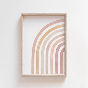 May include: A framed print of a watercolor rainbow in shades of pink, orange, and yellow. The rainbow is arched and has a white background.