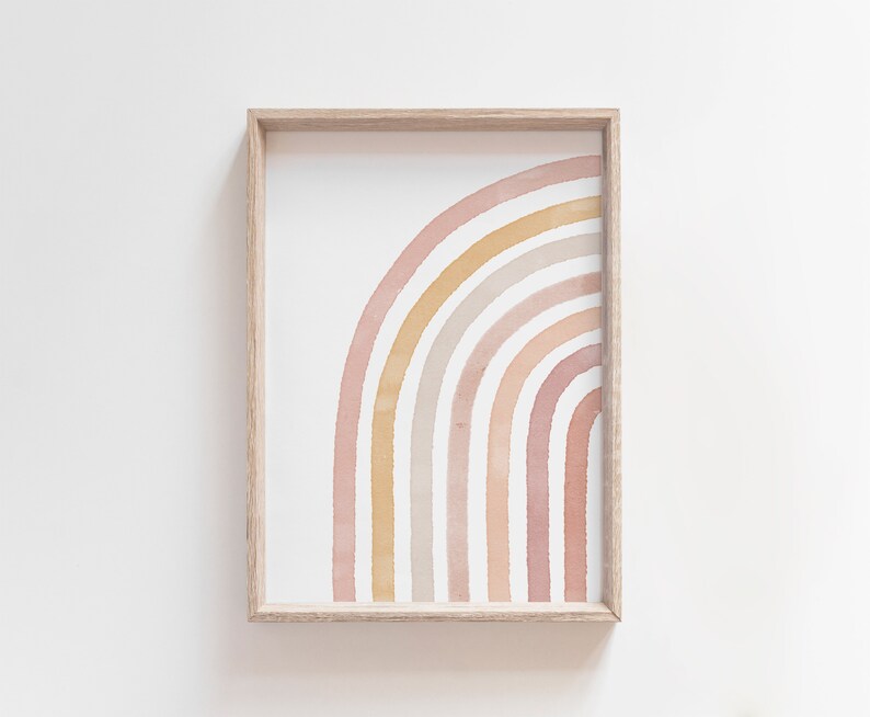 May include: A framed print of a watercolor rainbow in shades of pink, orange, and yellow. The rainbow is arched and has a white background.