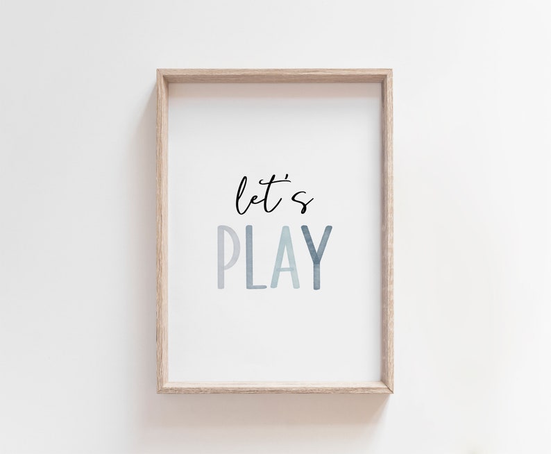 May include: A framed print with the text "let's PLAY" in a blue watercolor gradient. The frame is light wood.