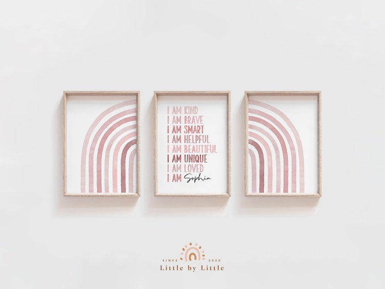 May include: Three framed prints featuring a pink watercolour rainbow design. The centre print includes the text "I am kind, I am brave, I am smart, I am helpful, I am beautiful, I am unique, I am loved, I am Sophia".