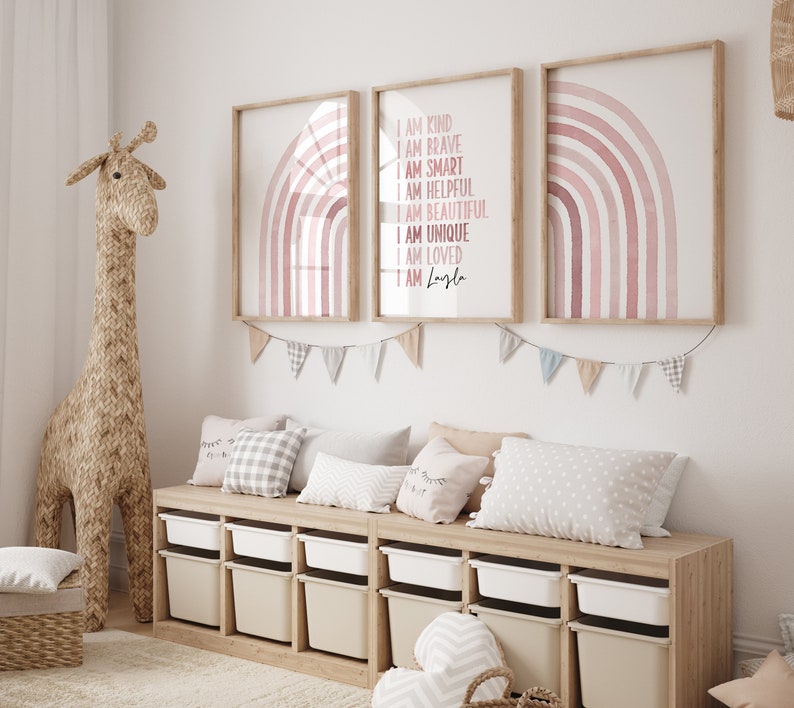 May include: Three framed prints featuring pink watercolour rainbows. The centre print includes the text "I am kind, I am brave, I am smart, I am helpful, I am beautiful, I am unique, I am loved, I am Layla".