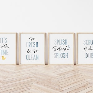 May include: Four framed prints with blue and white watercolor designs and black text. The prints read "It's Bath Time" with a yellow rubber duck, "So Fresh & So Clean", "Splish Splash Splosh", and "Scrub A Dub Dub".