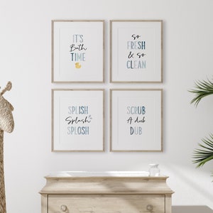 May include: Four framed prints with blue and white watercolor text on a white background. The prints feature bathroom-themed phrases: "It's Bath Time", "So Fresh & So Clean", "Splish Splash Splosh", and "Scrub A Dub Dub".