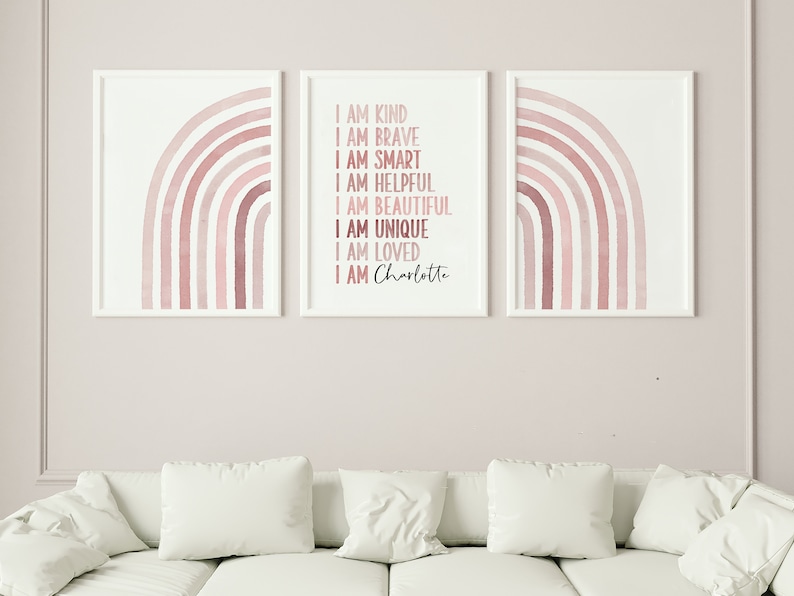 May include: Three framed prints featuring a pink watercolour rainbow design. The centre print includes the text "I am kind, I am brave, I am smart, I am helpful, I am beautiful, I am unique, I am loved, I am Charlotte".