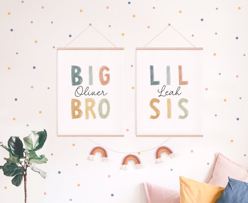 May include: Two framed prints with colorful text that reads "BIG Oliver BRO" and "LIL Leah SIS". The prints are hung on a white wall with a colorful confetti pattern.