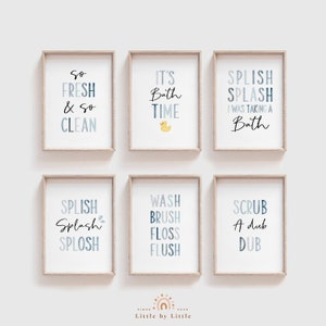 May include: Six framed prints with blue and white text on a white background. The prints feature bathroom-themed phrases like "So Fresh & So Clean", "It's Bath Time", "Splish Splash I Was Taking A Bath", "Splish Splash Splosh", "Wash Brush Floss Flush", and "Scrub A Dub Dub".