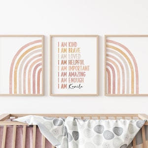 May include: Three framed prints with watercolor rainbows in shades of pink and yellow. The middle print has the text "I am kind, I am brave, I am loved, I am helpful, I am important, I am amazing, I am enough, I am Kamila".