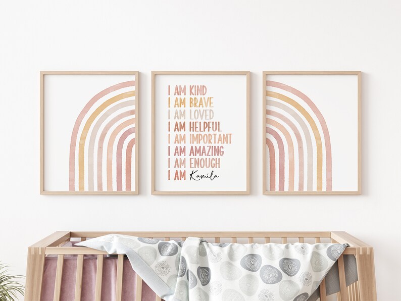 May include: Three framed prints with watercolor rainbows in shades of pink and yellow. The middle print has the text "I am kind, I am brave, I am loved, I am helpful, I am important, I am amazing, I am enough, I am Kamila".