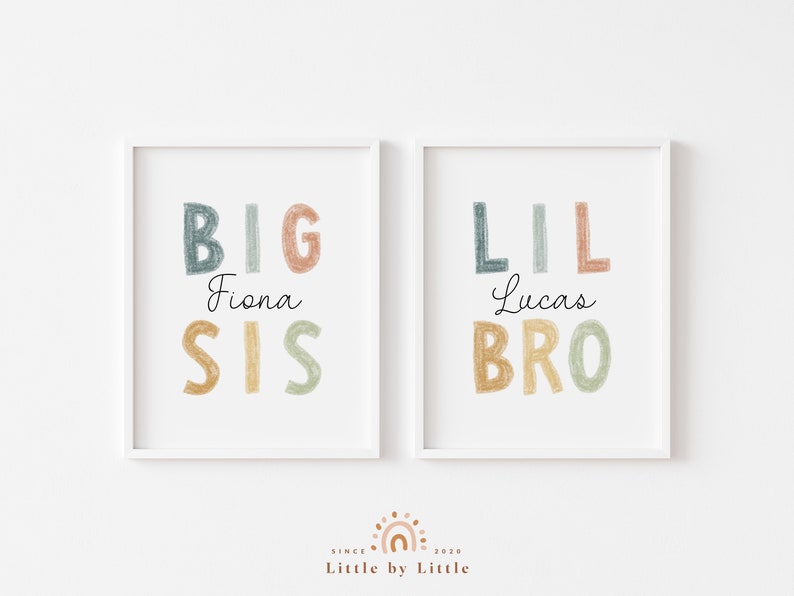 May include: Two white framed prints with colorful text. The left print says "BIG Fiona SIS" and the right print says "LIL Lucas BRO".