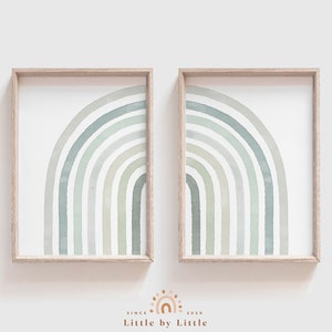 Op de afbeelding: Twee ingelijste prints van aquarel regenbogen in tinten groen en grijs. De regenbogen zijn in een moderne minimalistische stijl.