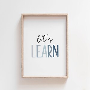 May include: A framed print with the text "let's learn" in a blue watercolor gradient. The frame is a light wood color.