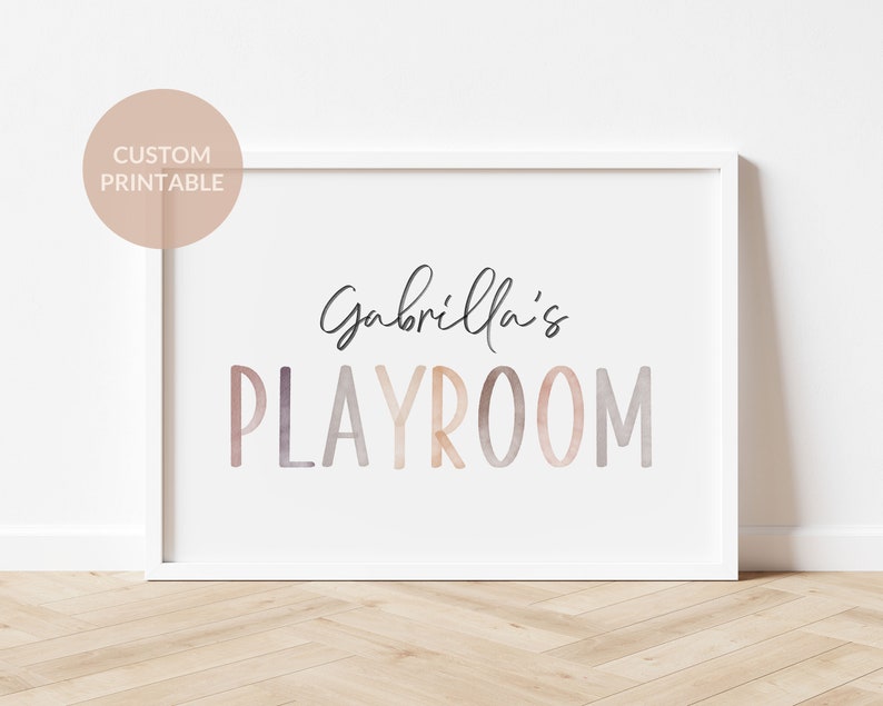 May include: A white framed print with the text "Gabriella's Playroom" in a watercolor-style font with pink, orange, and purple hues.