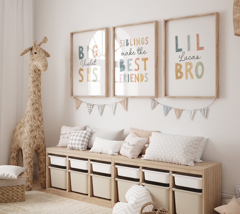 May include: Three framed prints with colorful text on a white wall. The prints say "Big Sis Violet", "Siblings make the best friends", and "Lil Bro Lucas".