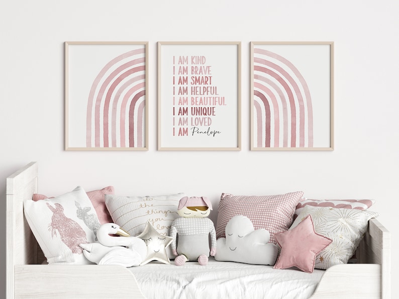 May include: Three framed prints featuring pink watercolour rainbows. The centre print includes the text "I am kind, I am brave, I am smart, I am helpful, I am beautiful, I am unique, I am loved, I am Penelope".