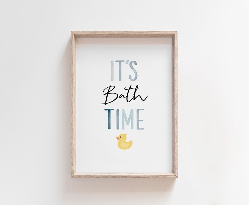 May include: A framed print with the text "It's Bath Time" in blue and black lettering. A yellow rubber duck is pictured below the text.